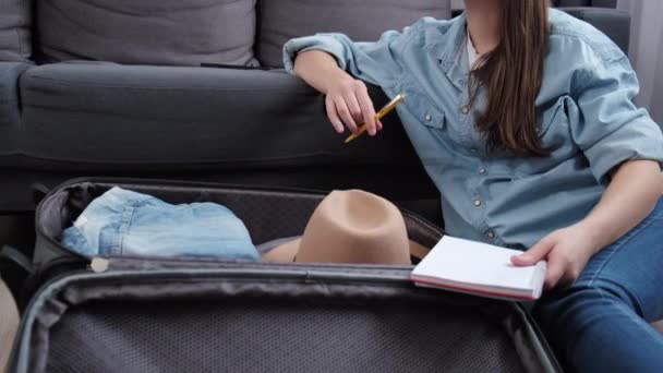 Mujer Joven Triste Sosteniendo Pluma Portátiles Maleta Embalaje Sentado Sofá — Vídeo de stock