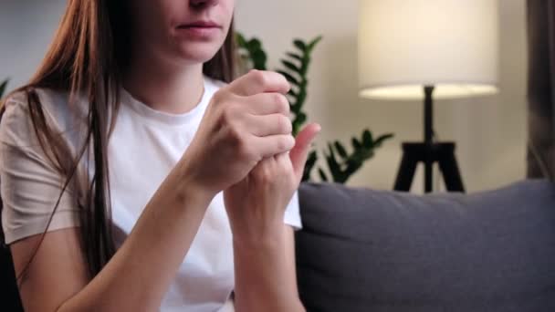 指の痛み 関節炎と指の関節痛を持つ病気の若い女性が自宅でソファに座っている 慢性痛風の症状を持つ女性の手のクローズアップ 健康管理 簡単な自己マッサージの概念 — ストック動画