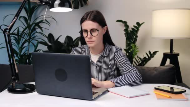 戴眼镜的年轻高加索女人坐在桌旁的沙发上 工作着笔记本电脑 感觉耳朵疼痛 不愉快的烦躁的女商人或女学生 带状疱疹 腮腺炎概念 — 图库视频影像