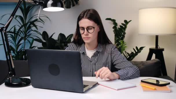 手指疼痛的概念 戴眼镜的年轻女性在键盘笔记本电脑上发短信 手指关节感到疼痛和不适 和坐在办公室里的电脑一起工作时的愤怒和痛苦 — 图库视频影像