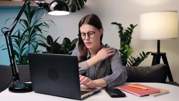 颈部疼痛 神经抽筋 肌肉紧张 颈椎病的概念 疲惫的年轻白种女人 头戴眼镜片 脖子酸痛 晚上坐在办公室的沙发上 — 图库视频影像