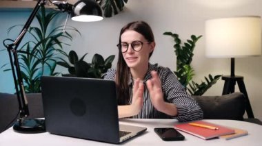 İnternetteki sanal sohbet buluşmasında konuşan mutlu bir bayan bilgisayar görüntüsü kullanıyor. Gülümseyen kadın videosu bilgisayarlı web kamerası konferansını kullanarak iş görüşmesi istiyor. Ev ofisindeki koltukta otur.