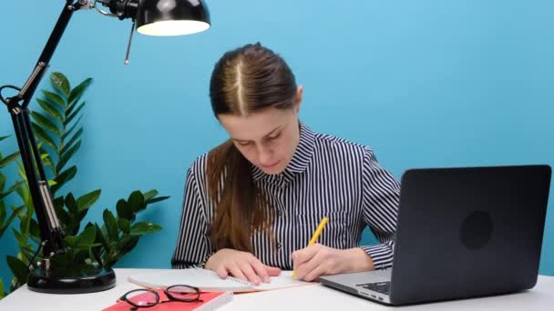 专注于电脑和打字的年轻女商人坐在白色的写字台前 与客户交流 与蓝色背景隔离 负责项目的国际女员工 — 图库视频影像