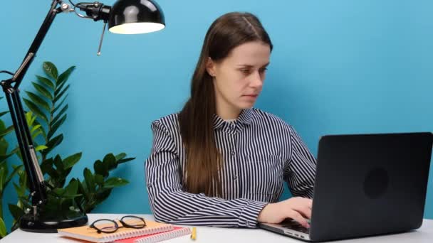秘密の成功した従業員の肖像カジュアルなシャツのビジネスマンの女性は ノートパソコンとオフィスの机で仕事に座ると言う急いで唇の上に指で静かにShhジェスチャー 青の背景スタジオ上に隔離されたポーズ — ストック動画