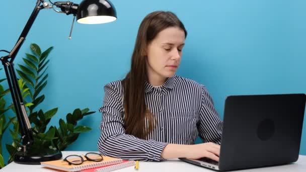 疲惫困倦疲惫的职业女性穿着休闲服坐在写字台前工作 电脑膝上型电脑打呵欠 在工作室的淡蓝色背景墙上显得孤立无援 — 图库视频影像