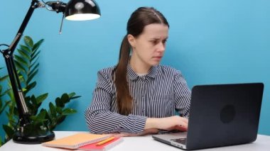 Ciddi bir çalışan iş kadını. Günlük gömlekli. Ofis masasında bilgisayarlı çalışıyor. İşaret parmağı kamerasını komutunuza doğrultuyor.