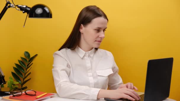 成功した従業員の女性の肖像20代は スタジオで黄色の背景壁の上に隔離されたポーズ 落ち着こうとするリラックスした瞑想ヨガのジェスチャーでノートパソコンの手でホワイトオフィスデスクで仕事に座る — ストック動画