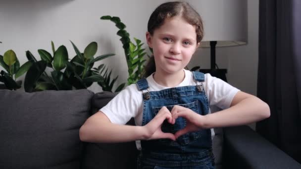Retrato Feliz Alegre Menina Fazendo Forma Coração Mão Sentado Sofá — Vídeo de Stock