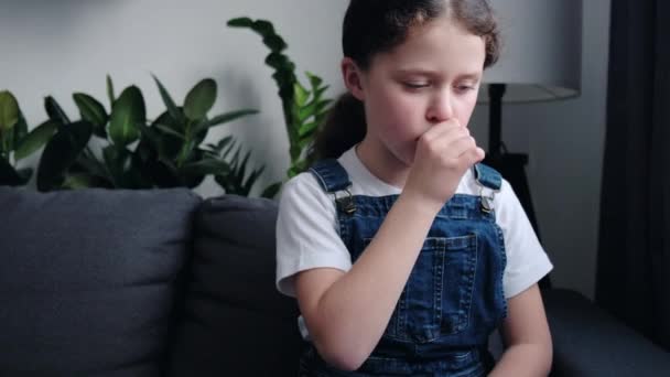 近照不健康的心烦意乱的小女孩抱着脖子坐在家里灰色的沙发上 喉咙疼痛 心绞痛 难以吞咽 声音丧失 儿童免疫概念 — 图库视频影像
