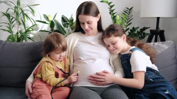 Érdekes Aranyos Kislányok Sztetoszkóppal Kezelik Terhes Anya Hasát Hallgatják Fiatalabb — Stock videók
