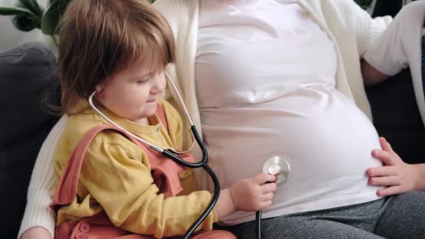 Close Cute Little Daughter Using Medical Stethoscope Listening Pregnant Mom — Stockvideo