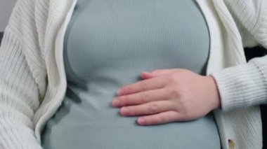 Oturma odasındaki koltukta oturan üzgün hamile kadının seçici odak noktası. Boynunda ağrı, omuzlarında masaj ve hamilelik sırasında kaslar gerilmiş. Fibromiyalji kavramı