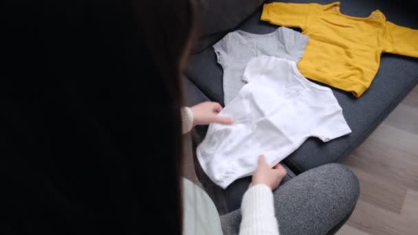 Side View Pregnant Woman Holding Baby Clothes Hands Packing Baby — Video