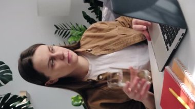 Dizüstü bilgisayarda çalışan güzel 20 'li yaşlarda genç bir kadının dikey görüntüleri bağımsız olarak mesajlaşma, ara verme, doğal maden suyu içme, yudumlamanın sağlığa önem vermesini sağlıyor. Günlük rutin konsept