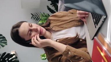 Mutlu, genç bir bayanın evdeki masasında oturup müşteriyle uzaktan telefon görüşmesi yaptığı, telefonla yardım aldığı dikey bir video. Tüm iş dünyası modern kablosuz teknoloji konseptini uzaktan çözer.