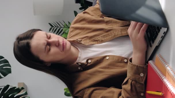 疲れ若い女性の寺院マッサージの垂直ショットは コンピュータの仕事の後 頭痛の種は 部屋のラップトップでテーブルに座っている 頭に触れる排気女の子 痛みを軽減 片頭痛の概念 — ストック動画