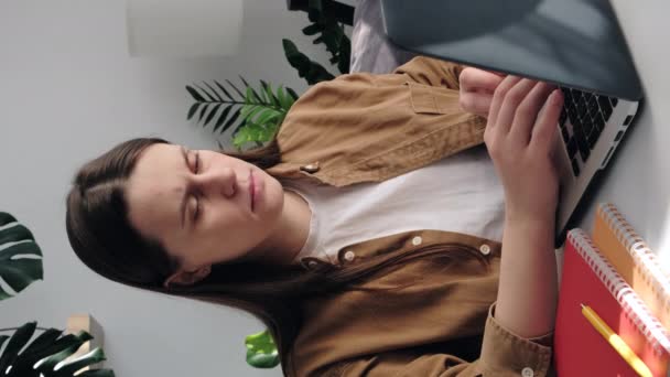 職場で悲しい若いブルネットの20代の女性を動揺させる垂直ショットはノートパソコンで動作し 頭の痛みを持って 彼女は頭に冷たい水のガラスを傾きます ハングオーバー 高または低血圧の概念 — ストック動画