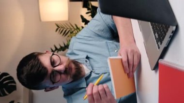 Bilgisayarla çalışan ve müşterilerle iletişim kuran genç iş adamlarının dikey görüntüleri. Odaklanmış adam uluslararası şirket çalışanı proje ve not almakla meşgul