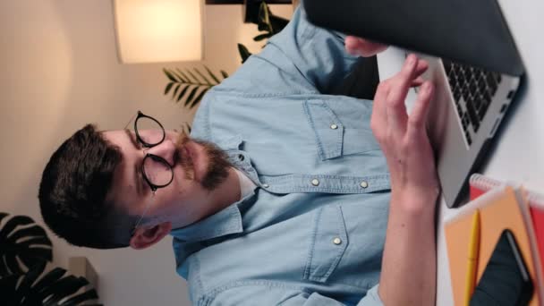 コンピュータの作業場所で眼鏡の中の若い髭の男の垂直ビデオや痛みを経験し 指の関節の不快感 指の痛み 関節リウマチ 痛風関節炎 関節症の概念 — ストック動画