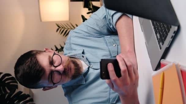 Bilgisayarı Modern Akıllı Telefonu Kullanan Ciddi Bir Gencin Dikey Videosu — Stok video