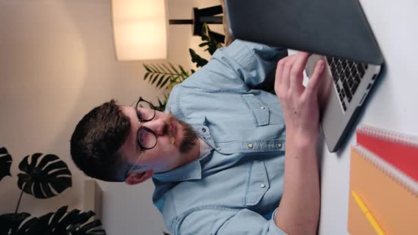 精疲力竭的年轻男性在眼镜中的垂直视频 患有眼部紧张 干眼症 眼睑按摩 坐在沙发上疲倦 长时间使用笔记本电脑会使商家感到疲劳 — 图库视频影像