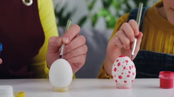 어머니와 식탁에 휴가를 준비하면서 달걀들을 손으로 그리는 모습을 가까이 수있다 — 비디오
