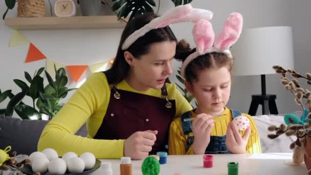 Cuidar Joven Madre Enseñando Hermosa Hija Pintar Huevos Sentados Juntos — Vídeo de stock