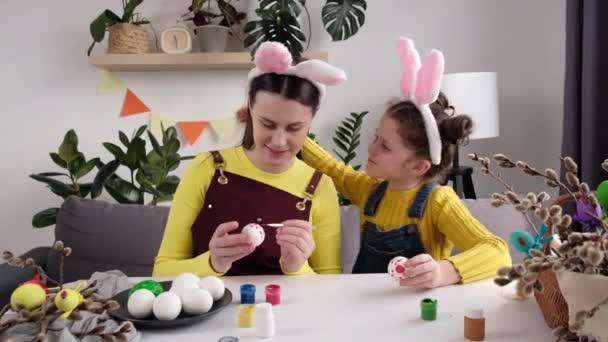 스러운 귀여운 식탁에 계란을칠 어머니에게 부드럽게 입맞추고 부활절을 준비하는 아이와 — 비디오