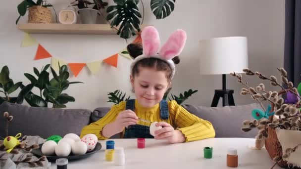 분홍색 귀여운 아기가 부활절 기념행사를 준비하고 테이블에 계란에 페인팅을 귀여운 — 비디오