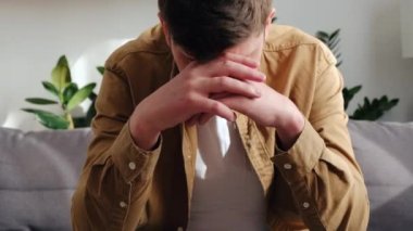 Stresli, üzgün, beyaz bir adamın oturma odasında kanepede tek başına oturması ve yüzünü ellerle kapatması. Depresyondaki 30 'lu yaşlardaki erkek kendini üzgün ve mutsuz hissediyor. Sorunlar ve panik atak konsepti