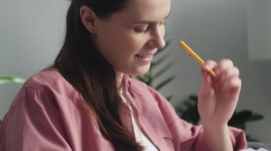 Mutlu, gülümseyen genç bir kadının seçici odak noktası rahat bir koltukta oturup günlüğe ya da deftere yazması. Müstakbel annenin alışveriş listesi. Hamilelik, insanlar ve eğlence konsepti