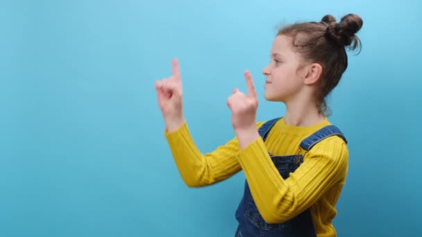 8岁穿着衣服的小女孩的肖像用手指把相机对准你 复制广告空间 在蓝色的背景工作室里摆出孤立的姿势 童年生活方式概念 — 图库视频影像