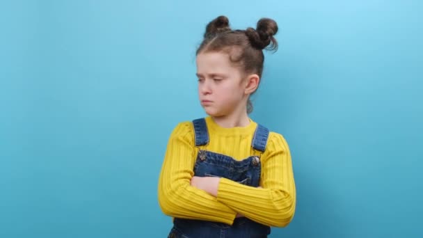8岁的小女孩手牵着手交叉交叉交叉 在工作室的蓝色背景墙上摆出孤立无援的形象 童年生活方式和情感概念 — 图库视频影像