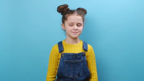 8岁穿着休闲装 开朗迷人 可爱的小女孩的画像 在演播室里吹气亲吻 在蓝色的背景墙上摆出孤身一人的姿势 童年生活方式概念 — 图库视频影像