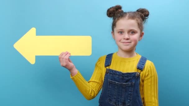 Χαμογελώντας Χαριτωμένο Μικρό Κοριτσάκι Κρατώντας Κατά Μέρος Κίτρινο Βέλος Δείχνοντας — Αρχείο Βίντεο