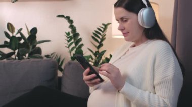 Evde cep telefonu kullanan, arkadaşlarıyla ya da akrabalarıyla video görüşmesi yapan, internette sohbet eden, gelecekteki annesi el sallayan, selamlayan, keyifli sohbetlerden zevk alan, kulaklıklı genç hamile bir kadın.