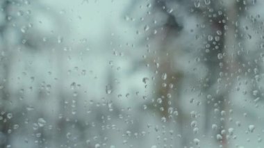 Yağmur damlasını kapat ve arka planda bulanıklık olan pencereye kar yağdır. Kar fırtınası günü büyük yağmur damlaları pencereyi vurur. Saf yağmur damlaları. Seçici odak