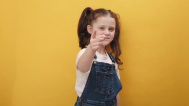 Hey sen! Genç kızın portresi heyecanla gülümsüyor ve kamerayı işaret ediyor, şanslı talihliyi seçiyor, en iyisini gösteriyor, sarı arka plan duvarında izole edilmiş bir şekilde duruyor stüdyoda.