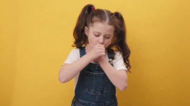 Sağlıksız çocuk portresi öksürürken ağızlarını eliyle kapatıyor, kötü hissediyor, alerji ya da viral enfeksiyon belirtileri gösteriyor, sarı arka plan duvarında izole bir poz veriyor. Hastalık, grip, enfeksiyon konsepti