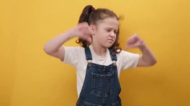 Konseptten hoşlanmadım. Mutsuz ergen kız çocuğu işaret dilini gösteriyor, hoşnutsuzluğunu, tatminsizliğini, tatminsizliğini dile getiriyor, stüdyodaki sarı arkaplan duvarında izole edilmiş bir poz veriyor.