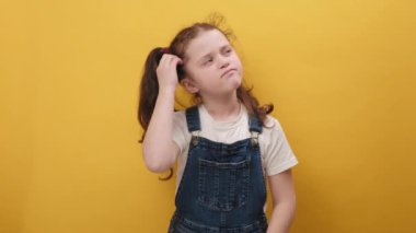 Portrait of pensive caucasian little kid girl gesturing with raised palms, frowning, being displeased and confused with dumb question, posing isolated over blue color background wall in studio