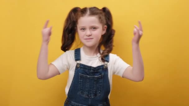 一个喜形于色的小女孩的画像 她用手拿着摇滚的手势 带着疯狂的表情大喊是的 为成功感到高兴 在黄色的工作室背景下被隔离 酷标志概念 — 图库视频影像
