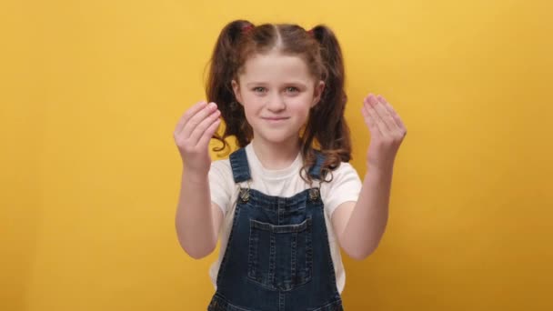 可爱有趣的小女孩的画像 表现出浪费钱或用手摆姿势 更多的小贴士梦想着大利润的身体语言 在演播室里把自己隔离在黄色的背景墙上 — 图库视频影像