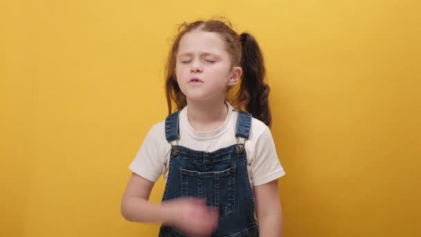 小女孩穿着休闲装 闻到难闻难闻难闻的气味 用手指捂住鼻子呼吸 在黄色背景下被隔离的形象 臭味概念 — 图库视频影像