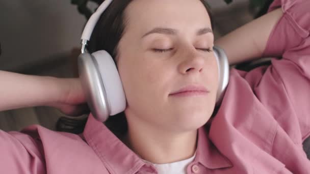 Zbliżenie Spokojnej Zrelaksowanej Młodej Kobiety Noszącej Słuchawki Słuchające Muzyki Opierającej — Wideo stockowe