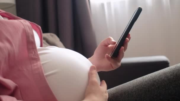 Zbliżenie Młodej Kobiety Ciąży Ubraniu Casual Siedzi Sam Wygodnej Kanapie — Wideo stockowe