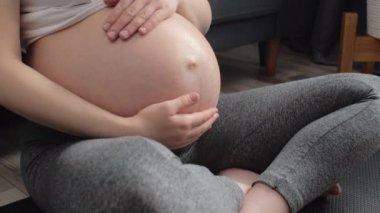 Sağlıklı hamilelik için meditasyon yapan ya da nefes egzersizleri yapan ve vücudu doğuma hazırlayan rahat hamile kadınlara yakın durun. Sakin, genç, beyaz, hamile anne evde yoga yapıyor.