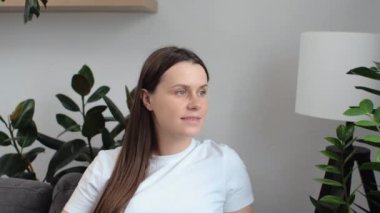Sevimli, huzurlu, hamile bir kadının portresi. Evde rahat bir koltukta oturup pencereye bakarak karnını okşuyor. Hamilelik sırasında gülümseyen beyaz kadın bebek bekliyor.