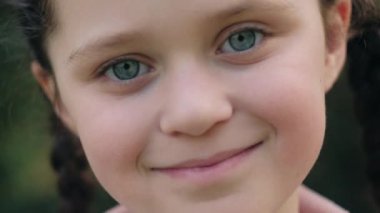 Çekici, gülümseyen küçük bir kızın yakın portresi. Mutlu bir şekilde kameraya bakıyor, baharın ya da yazın doğanın tadını çıkarıyor. Romantik ilham kaynağı yolculuk tutkusu. Macera ve seyahat konsepti