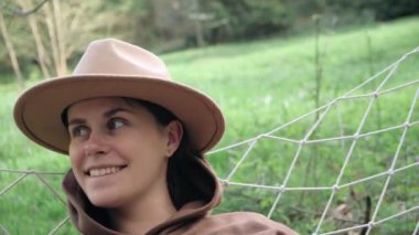 Gün ışığında hamakta sallanarak eğlenen neşeli genç bir kadının portresi. Mutlu kız yeşil ormanda bahar ya da yaz tatilinin tadını çıkarıyor. Pozitif duygular, insanlar zevk konsepti